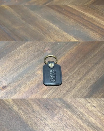 Silent 1080p hands-on video inspection highlighting the burnished edges, custom monogramming, and brass split ring of the handcrafted black leather key fob.