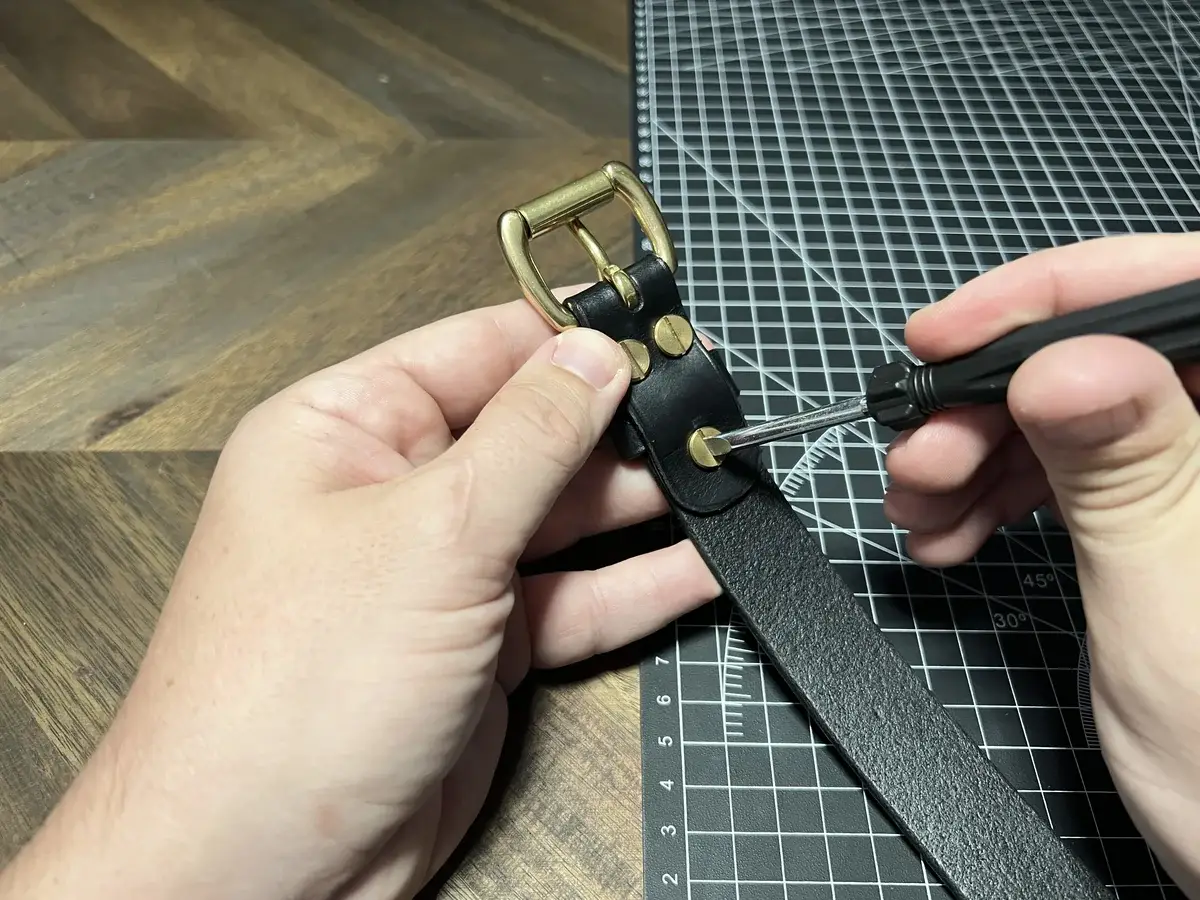 Setting the brass buckle and screws on a leather cuff by hand