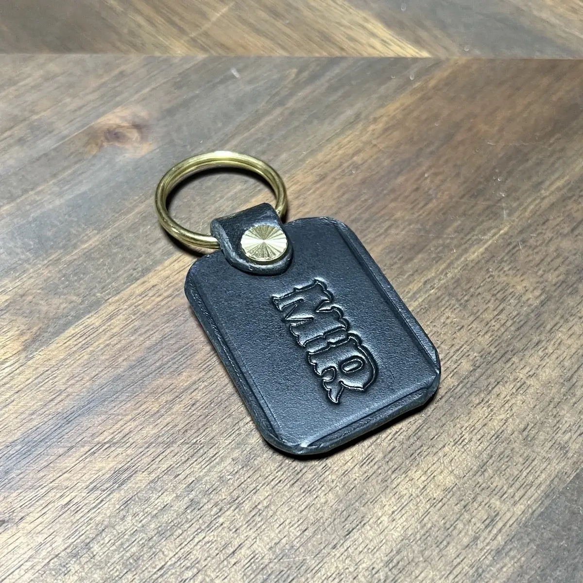 Black leather keychain with a brass ring and stamped initials